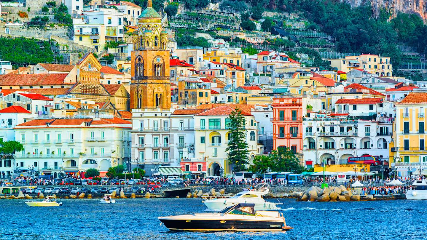 Scenery of colourful Amalfi town in autumn, with yacht floating on the sea in the foreground, Amalfi Coast