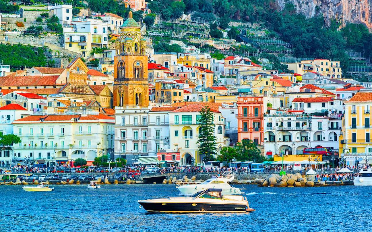 Scenery of colourful Amalfi town in autumn, with yacht floating on the sea in the foreground, Amalfi Coast