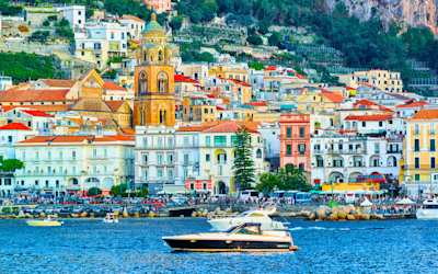 Scenery of colourful Amalfi town in autumn, with yacht floating on the sea in the foreground, Amalfi Coast