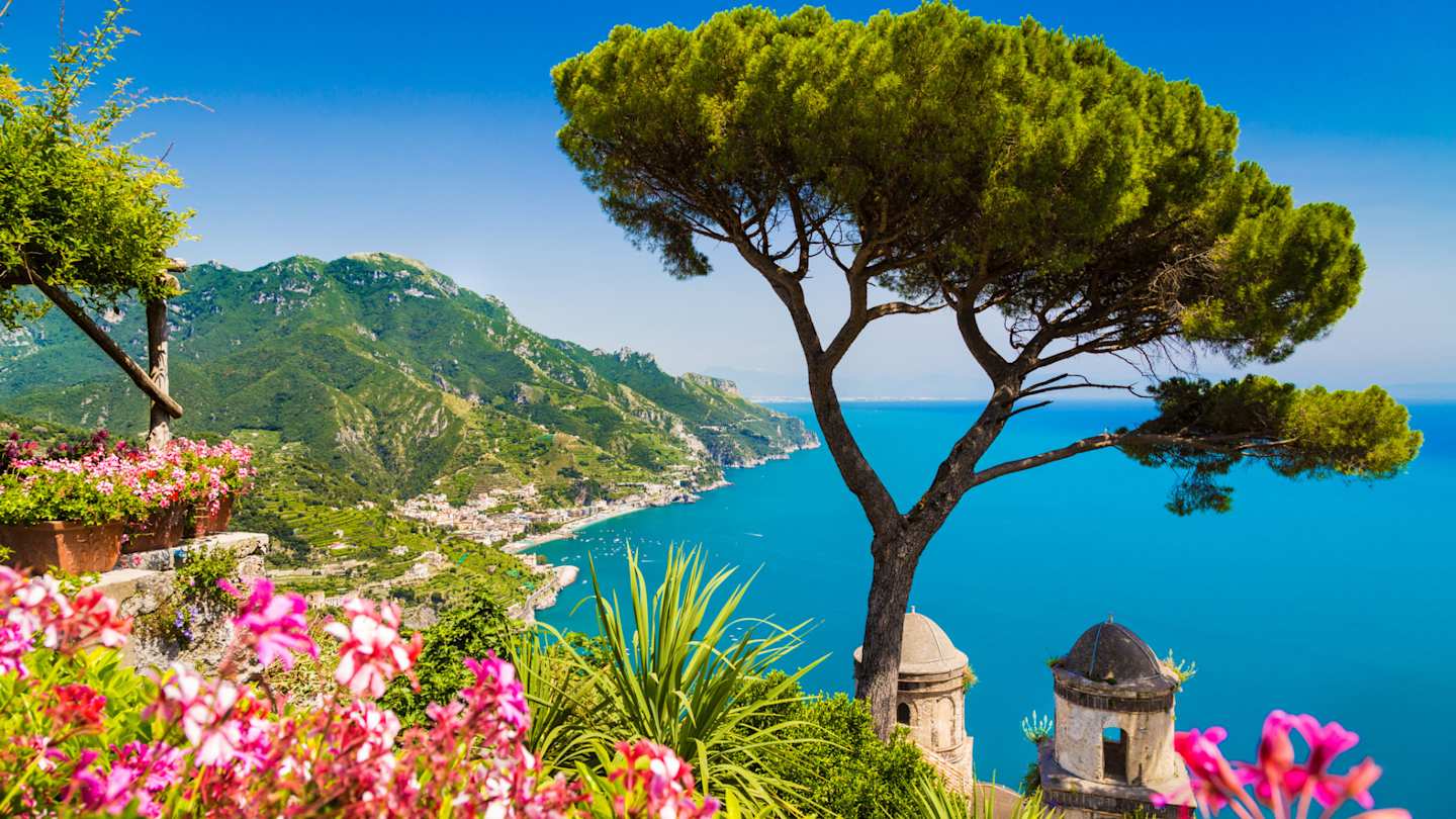 Scenic postcard view of Gulf of Salerno from Villa Rufolo gardens in Ravello, with pink flowers and tree, Amalfi Coast