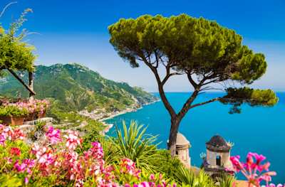 Scenic postcard view of Gulf of Salerno from Villa Rufolo gardens in Ravello, with pink flowers and tree, Amalfi Coast