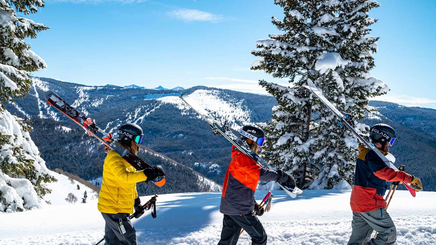 People walking on a mountain with skiing equipment in Vail, Colorado