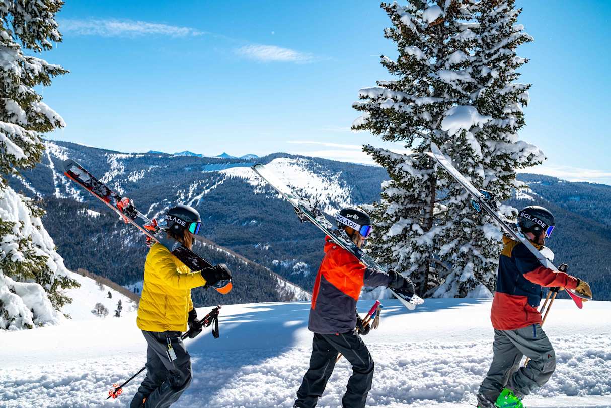 People walking on a mountain with skiing equipment in Vail, Colorado