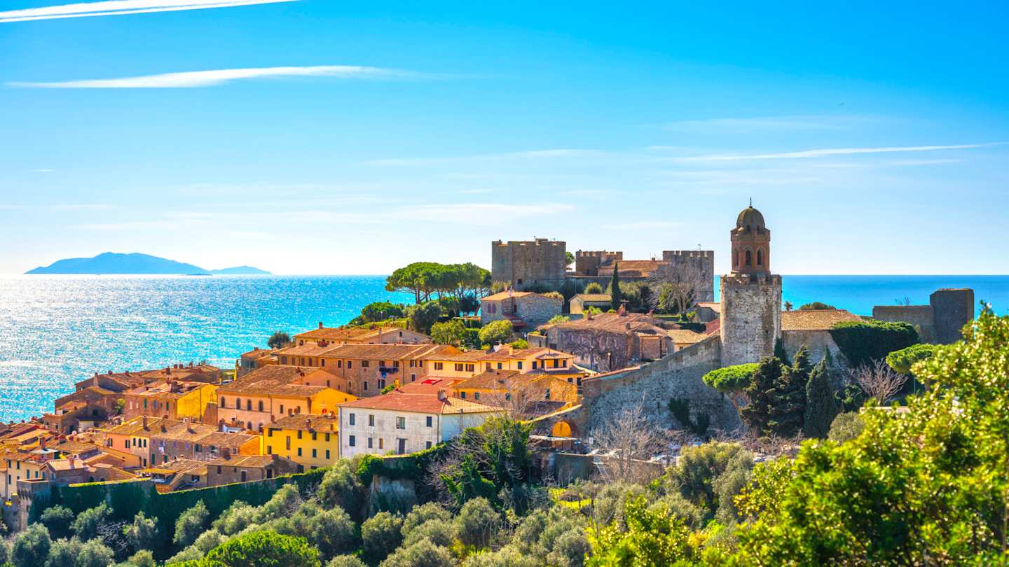 A view of Castiglione della Pescaia in the distance by the sea in summer, Tuscany, Italy