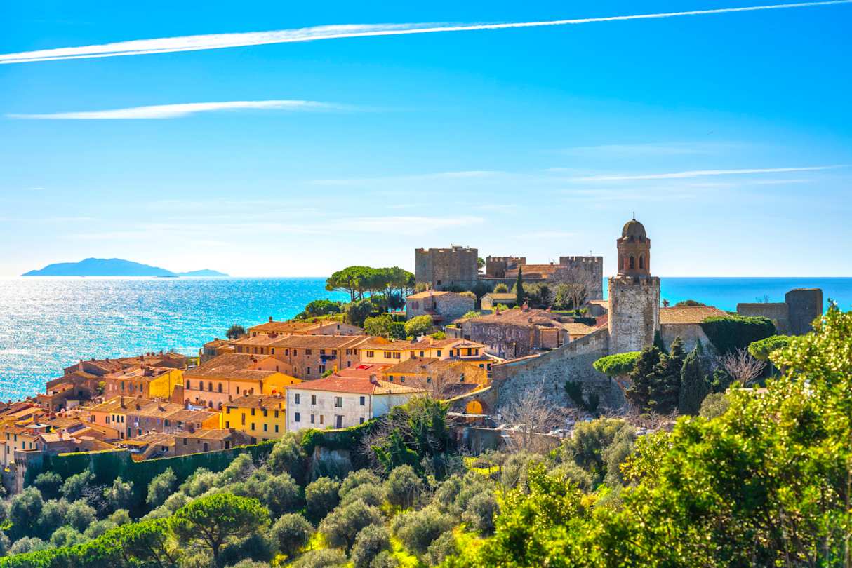 A view of Castiglione della Pescaia in the distance by the sea in summer, Tuscany, Italy