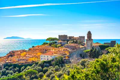 A view of Castiglione della Pescaia in the distance by the sea in summer, Tuscany, Italy