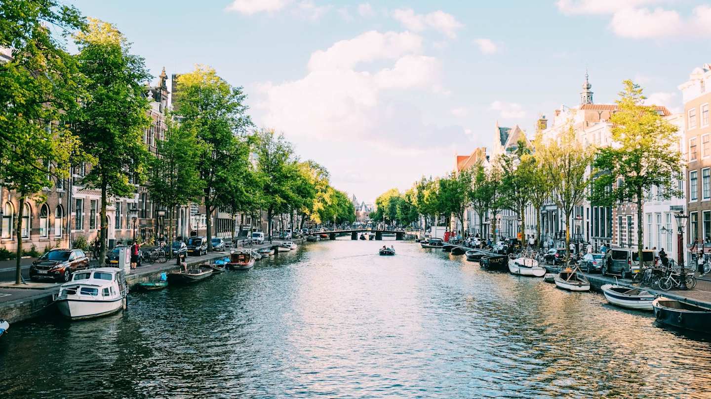 A canal filled with docked boats alongside terraced buildings, Amsterdam, Netherlands