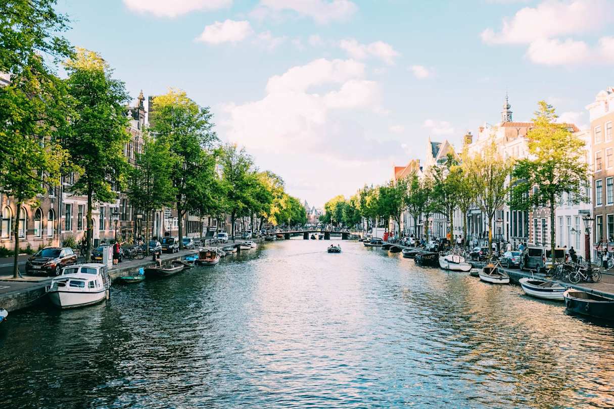 A canal filled with docked boats alongside terraced buildings, Amsterdam, Netherlands