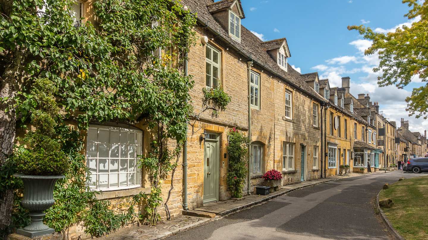 A row of honey-coloured stone cottages, some covered with vines, in Stow-on-the-Wold, Cotswolds, England
