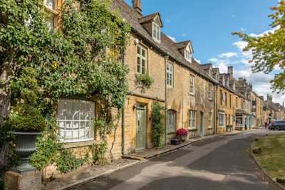 A row of honey-coloured stone cottages, some covered with vines, in Stow-on-the-Wold, Cotswolds, England