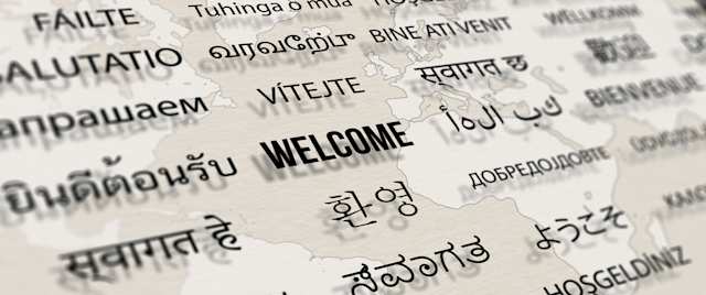 A sign displaying welcome messages in multiple different languages