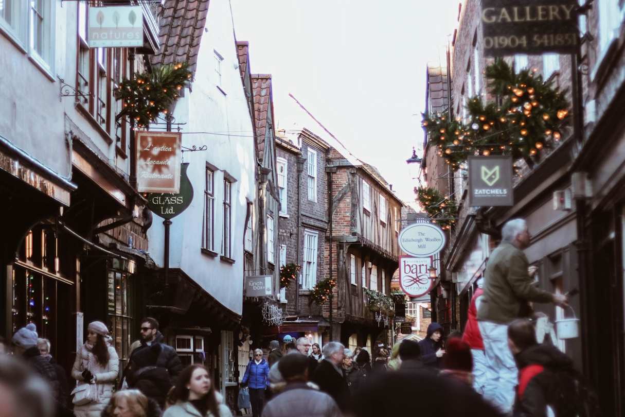 People walking along The Shambles in front of shops in York, England, UK