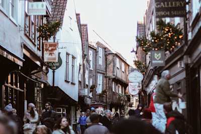 People walking along The Shambles in front of shops in York, England, UK