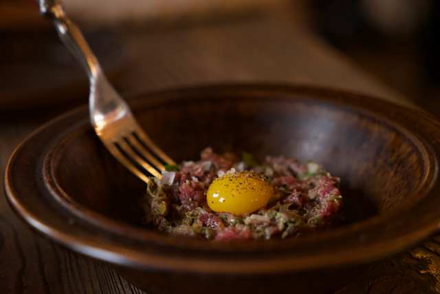 Close up view of a tatares meat steak with an egg yolk on top in a bowl at a restaurant