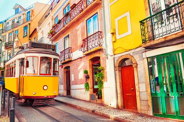 A yellow tram next to colourful buildings in Lisbon, Portugal