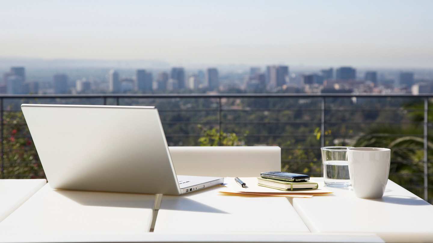 A laptop and work equipment on a desk overlooking a city skyline, USA
