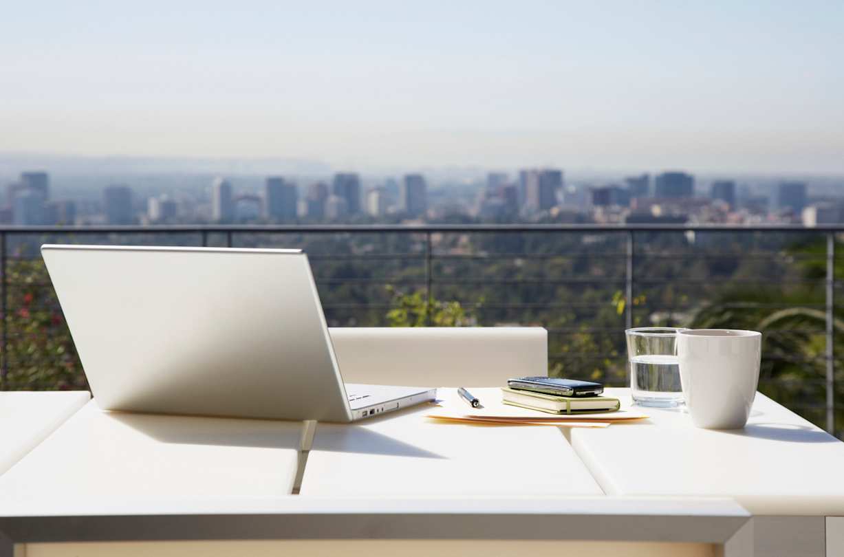 A laptop and work equipment on a desk overlooking a city skyline, USA