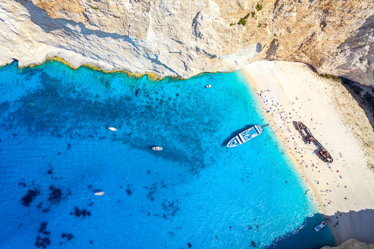 An bird's eye view of a boat in the water next to the sand at Navagio Beach, Zakynthos, Greece