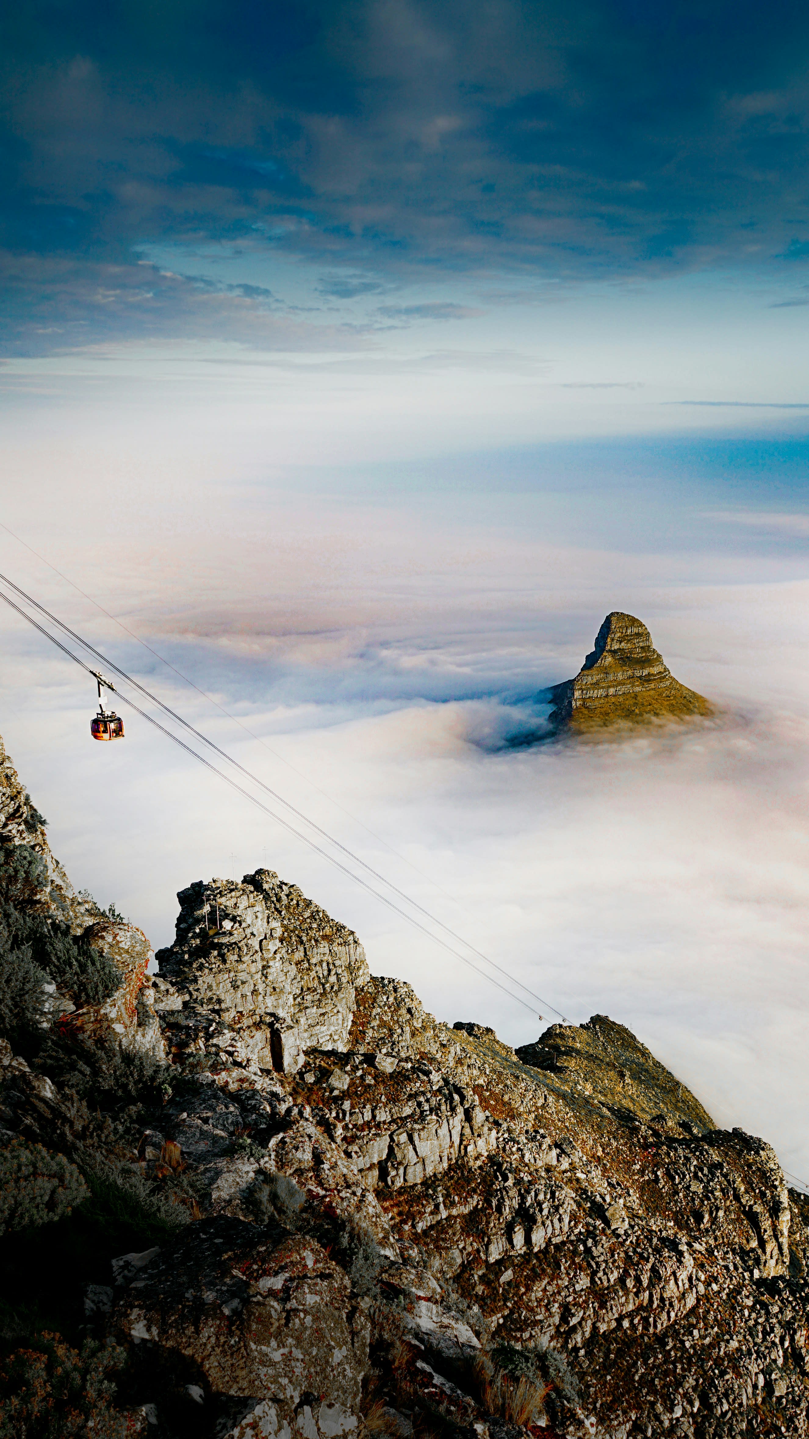 Lion's Head covered with a thick layer of clouds at sunrise, while a cable car descends down the mountain, Cape Town, South Africa