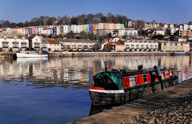 Boat on a canal in Bristol in front of colourful houses, England, UK
