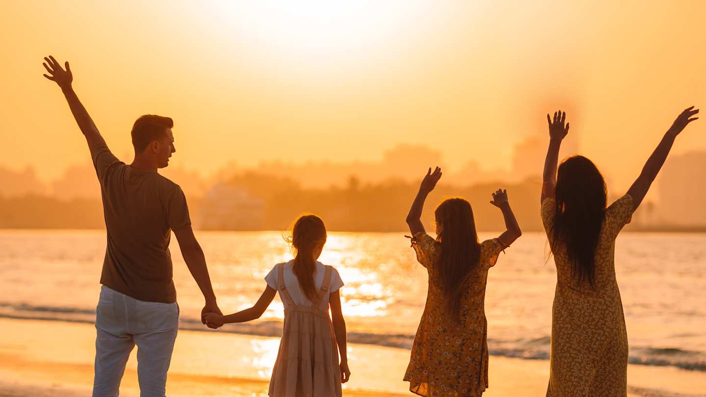 A young family enjoying the sunset from a sandy beach in Dubai, UAE