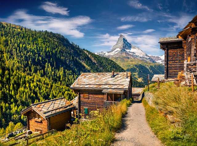 Wooden cabins in green hills by mountains in summer, Zermatt, Switzerland