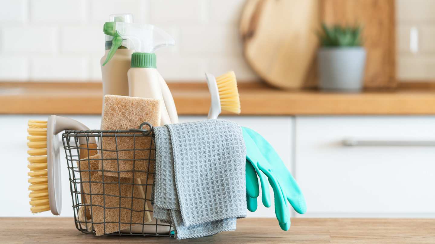 A close up view of cleaning products in a small basket on a kitchen counter