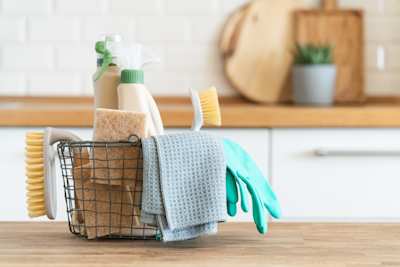 A close up view of cleaning products in a small basket on a kitchen counter