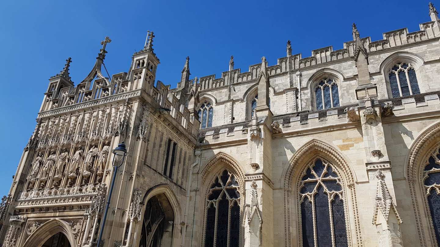 An exterior view of Gloucester Cathedral against a blue sky on a sunny day