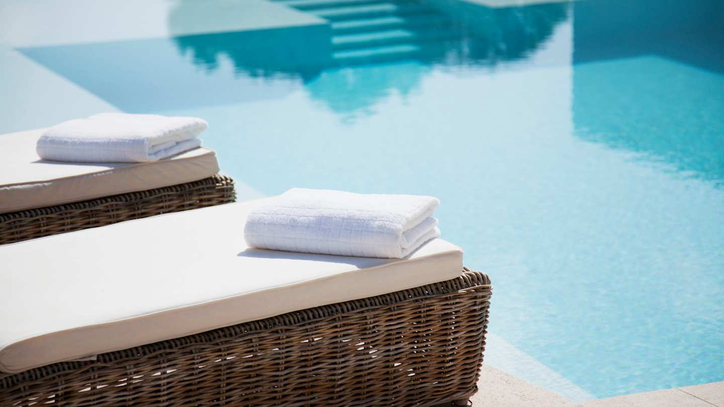 Neatly folded towels on sun loungers at a peaceful spa by a pool