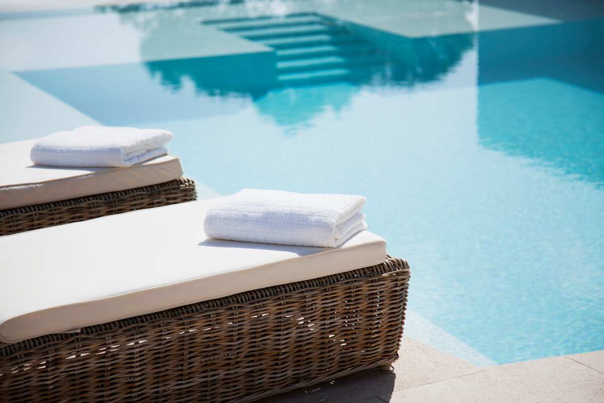 Neatly folded towels on sun loungers at a peaceful spa by a pool