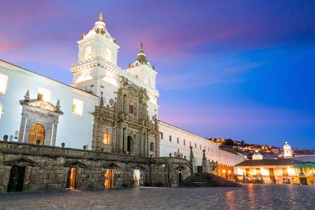 A large white building, the Plaza de San Francisco, in old town Quito, Ecuador at sunset
