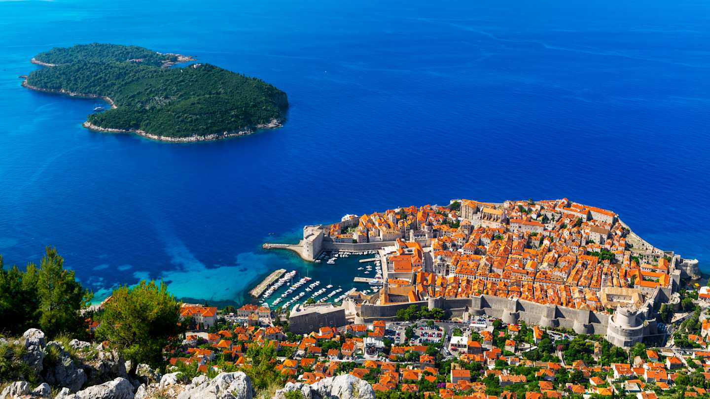 An aerial view of rooftops in the main city by the blue sea and a distant island in July, Dubrovnik, Croatia