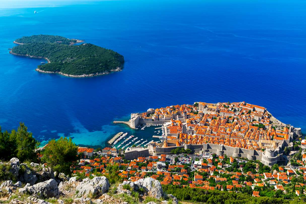 An aerial view of rooftops in the main city by the blue sea and a distant island in July, Dubrovnik, Croatia