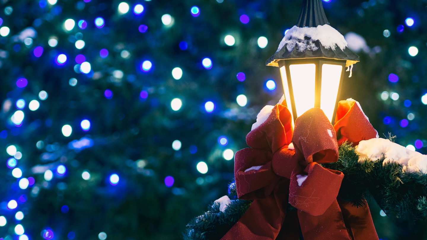 Lit, snow-covered lantern in front of a Christmas tree