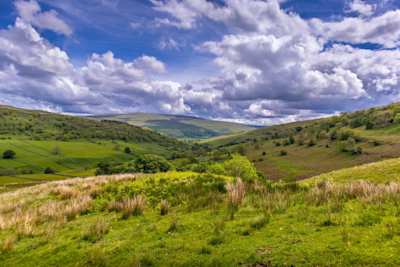 A view of large green meadows and hills on a sunny day in the Yorkshire Dales, England, UK