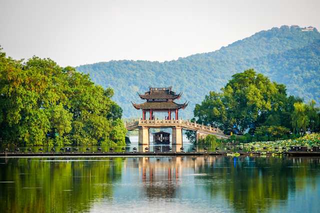 Yudai Bridge on a large lake near green trees and tall hills, Hangzhou ,China