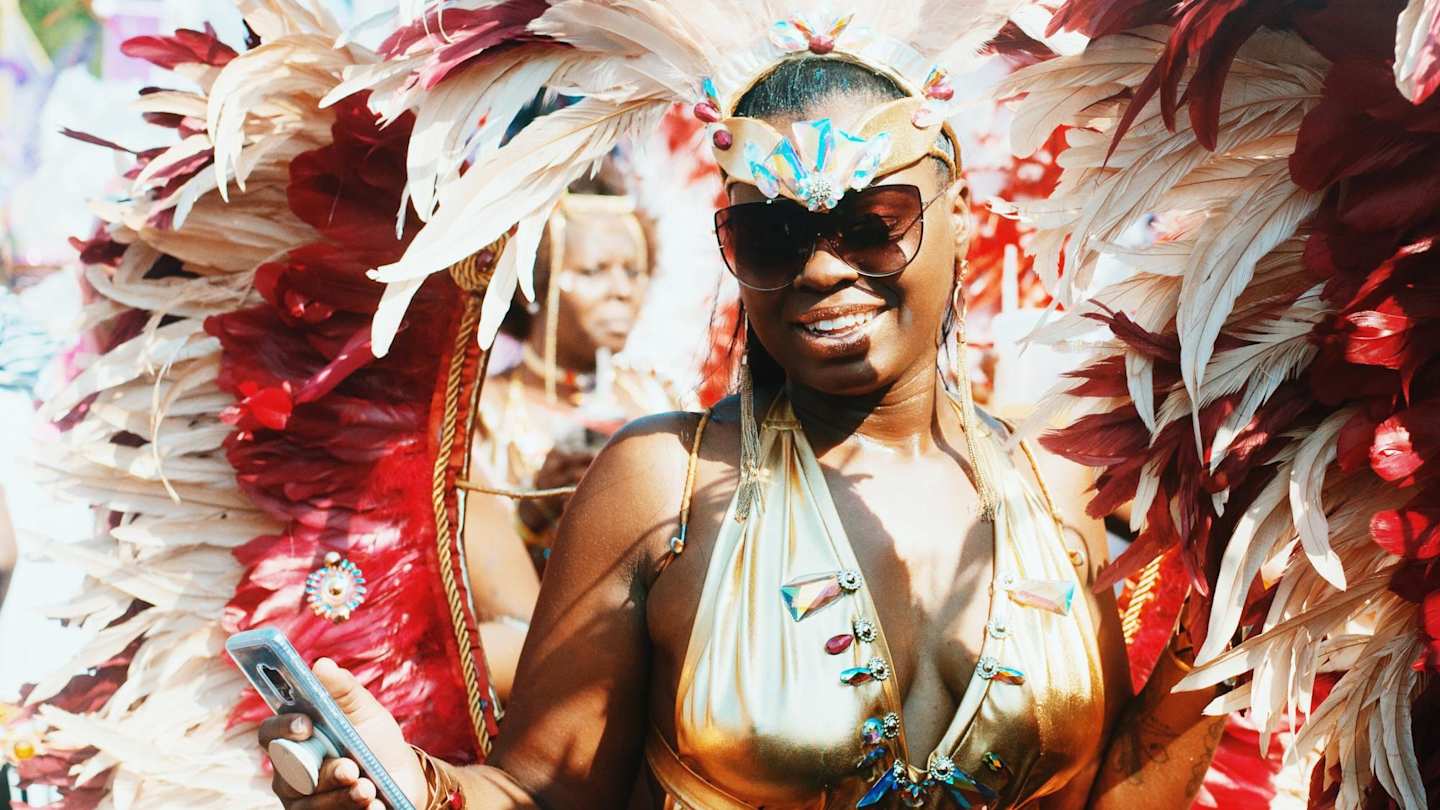 Young woman in fancy feathered costume celebrating Notting Hill Carnival, London