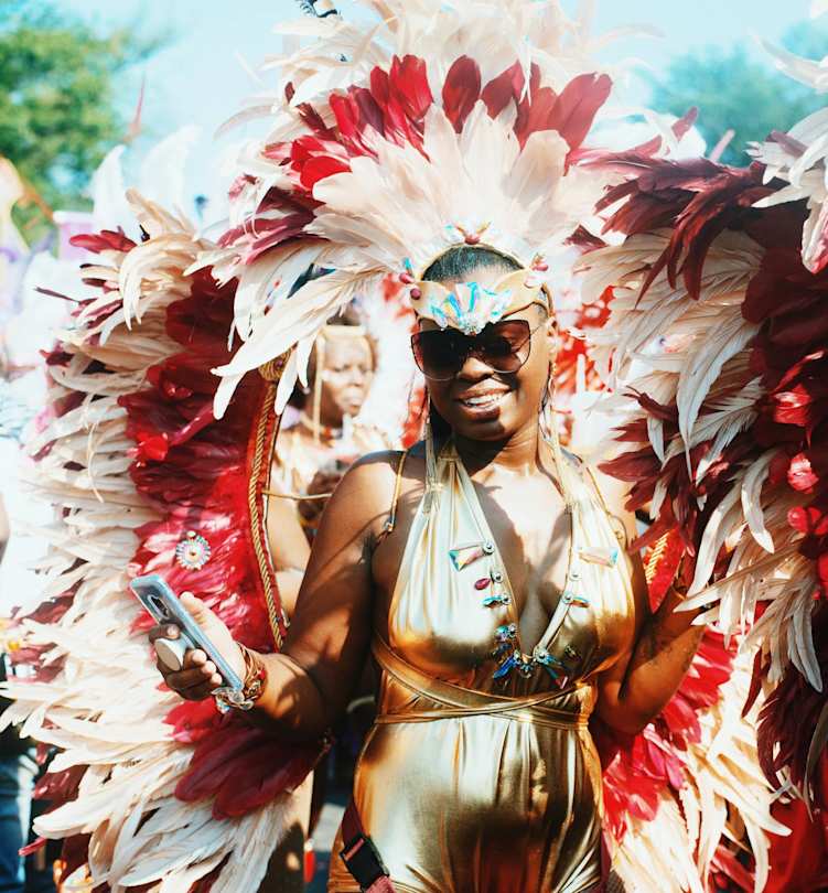 Young woman in fancy feathered costume celebrating Notting Hill Carnival, London