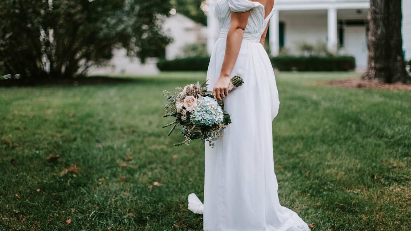 Bride holding bouquet of flowers in wedding dress