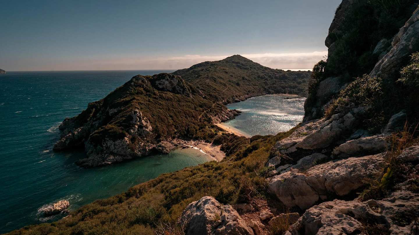 A view of a small beach underneath the mountains in Corfu, Greece from high up