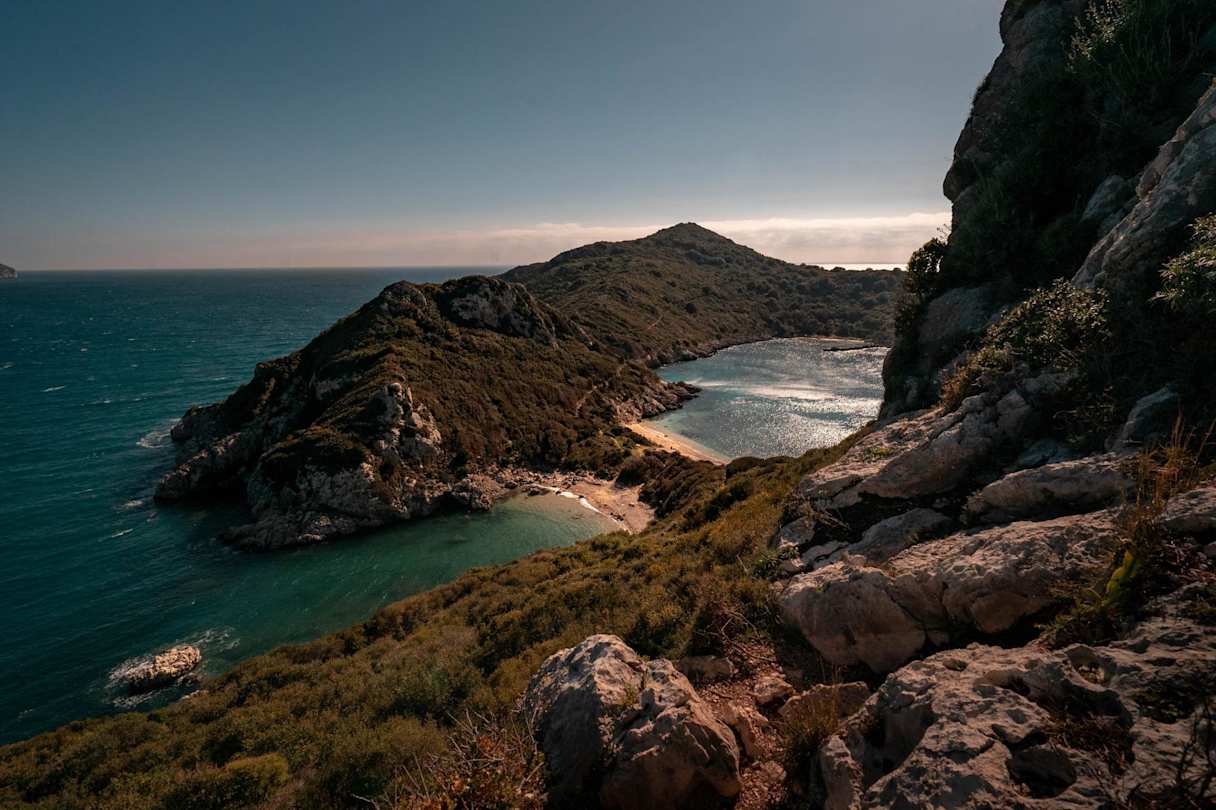 A view of a small beach underneath the mountains in Corfu, Greece from high up