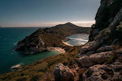 A view of a small beach underneath the mountains in Corfu, Greece from high up