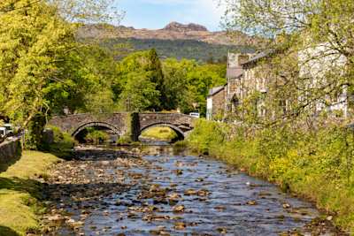 Attractive stone buildings and quaint bridge beside the River Glaslyn during autumn in Beddgelert, North Wales