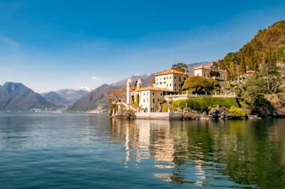 A large white building and hills next to Lake Como, Italy