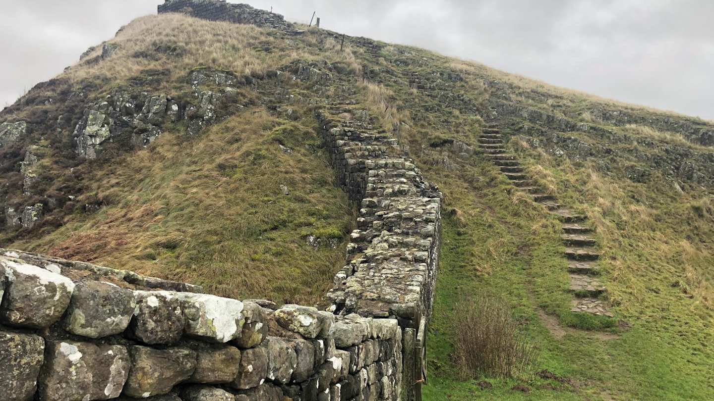 A close up view of Hadrian's Wall on a green hill on a misty day, Northumberland, England, UK