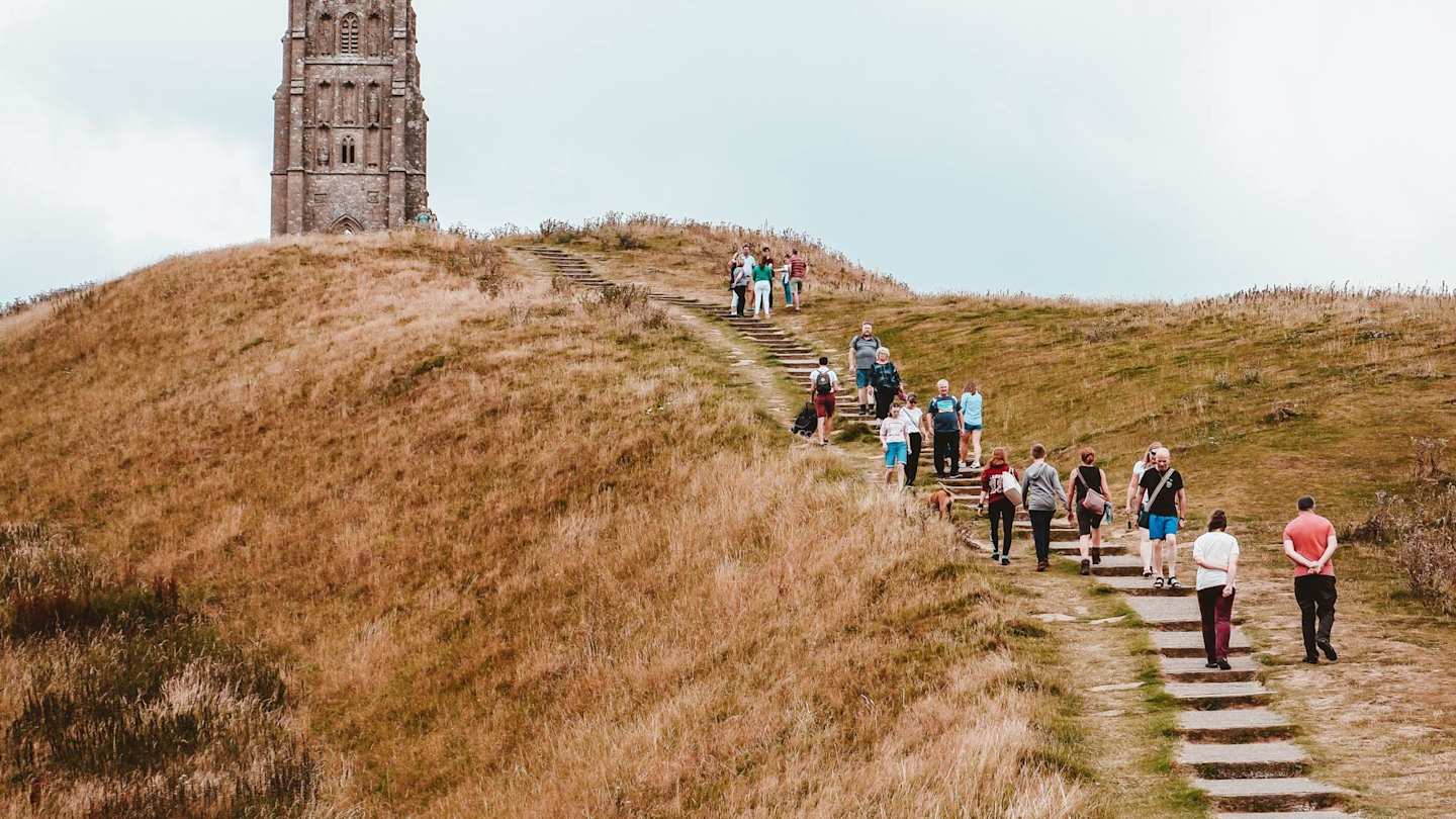 People walking up a hill to Glastonbury Tor, Somerset, England, UK