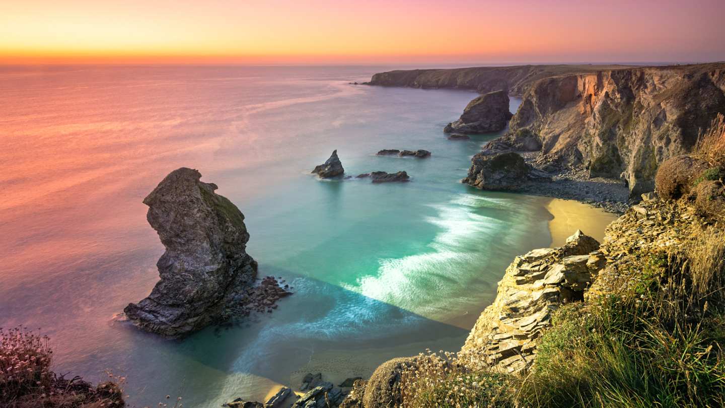 An aerial view of Carnewas and Bedruthan Steps in the sea at sunset, Cornwall, England, UK