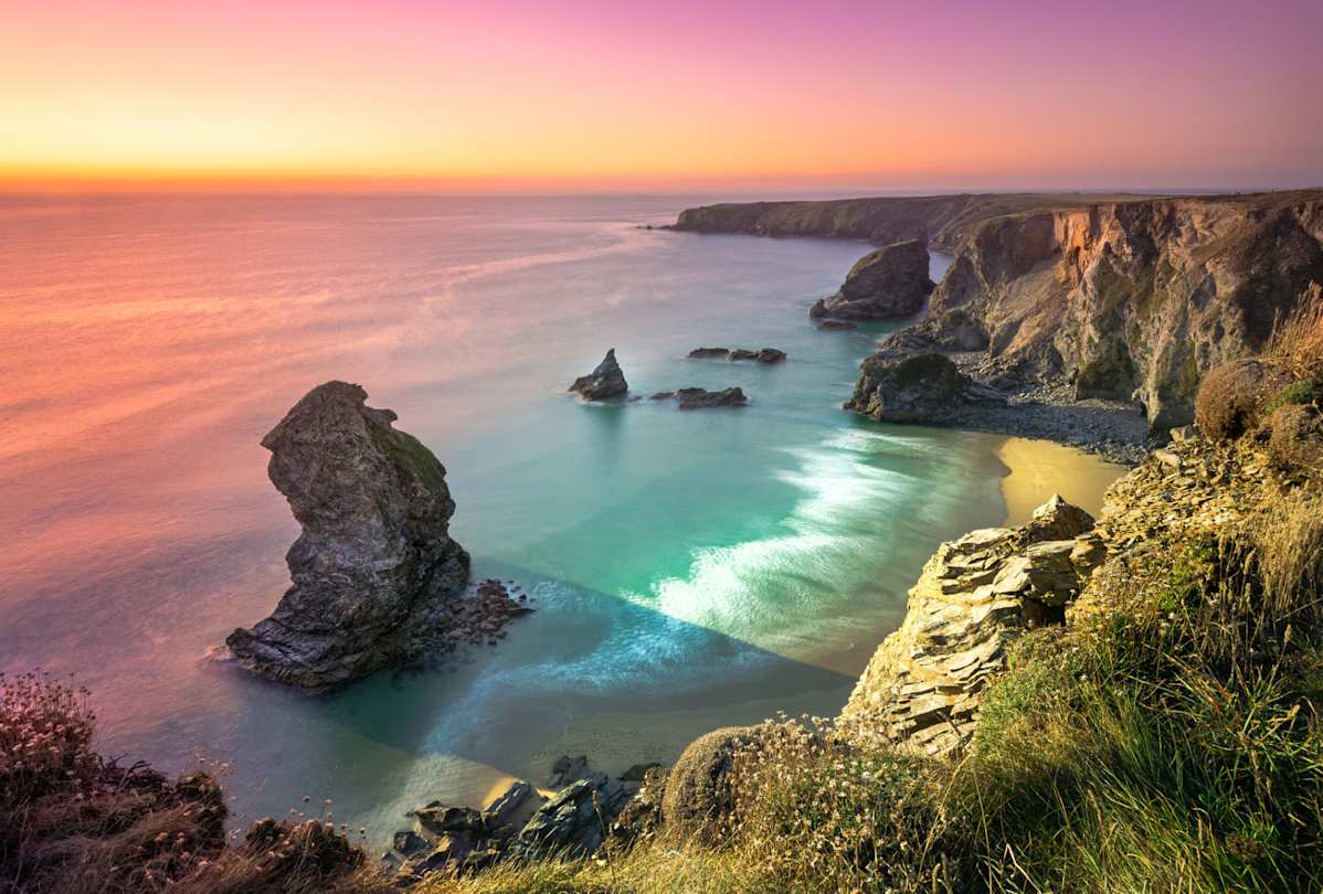 An aerial view of Carnewas and Bedruthan Steps in the sea at sunset, Cornwall, England, UK