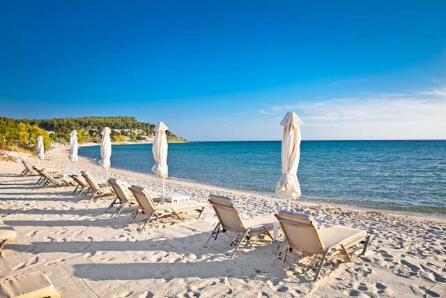 Sun loungers and parasols on the sand facing the sea at Sani Beach, Halkidiki, Greece